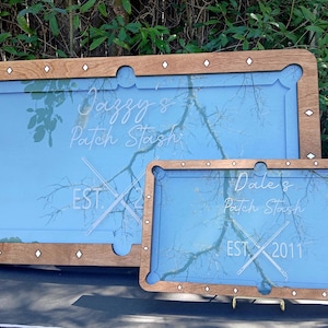 Puede incluir: Dos mesas de billar con marco de madera, fieltro azul y texto blanco. La mesa más grande dice "Jazzy's Patch Stash EST. 20" y la mesa más pequeña dice "Dale's Patch Stash EST. 2011".