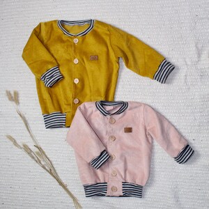 May include: Two corduroy jackets with striped cuffs. One jacket is mustard yellow and the other is light pink.