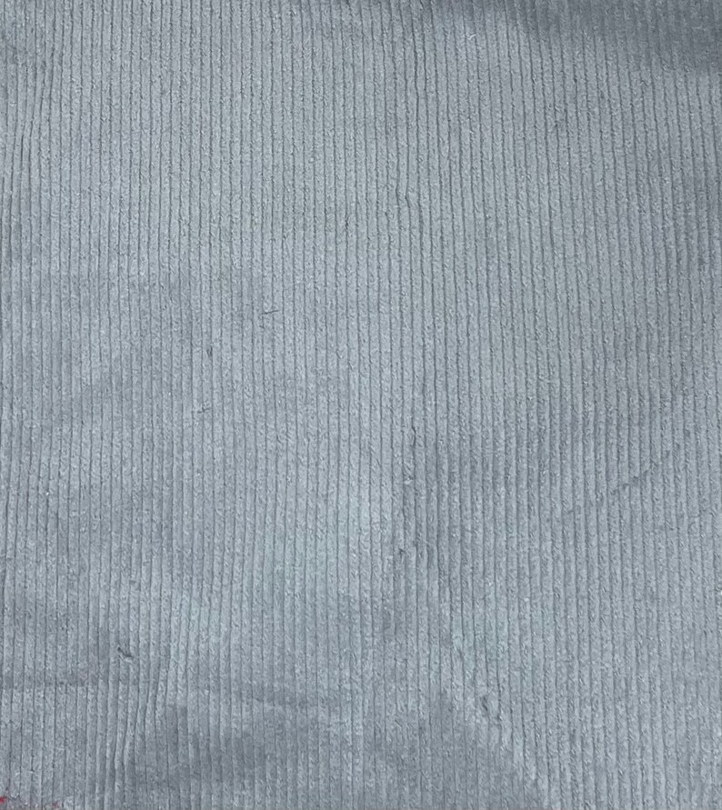 May include: A close-up of a gray corduroy fabric with a vertical ribbed texture.