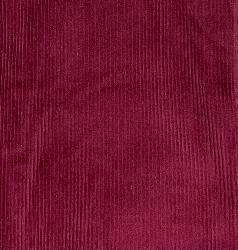 May include: A close-up of a deep burgundy corduroy fabric with a vertical ribbed texture.