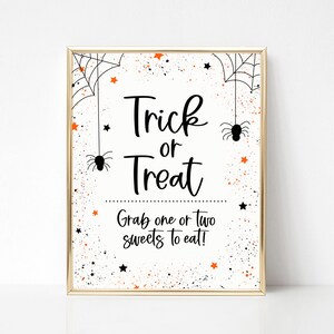 May include: A white sign with black text that says "Trick or Treat" and "Grab one or two sweets to eat!" The sign has a black and orange splatter background with black spiders and stars.