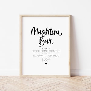 May include: A framed sign with the words "Mashtini Bar" in a stylish script font. Below, the text reads "Scoop some potatoes, load with toppings, enjoy!" in a simple, clean font. A small heart symbol is at the bottom.