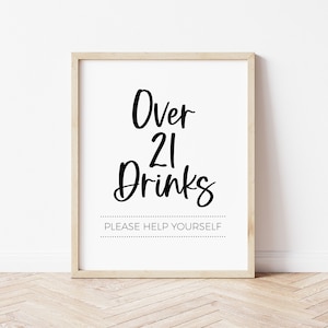 May include: A white sign with black text that reads "Over 21 Drinks" and "Please Help Yourself". The sign is framed in a light wood frame.