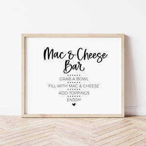 May include: A white sign with a wooden frame that reads "Mac & Cheese Bar" with instructions to grab a bowl, fill with mac & cheese, add toppings, and enjoy.
