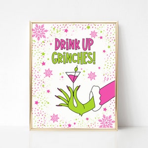 May include: A printable sign with a green hand holding a pink martini glass. The sign has a white background with pink and green confetti and the text "Drink Up Grinches!"