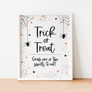May include: White sign with black text that says "Trick or Treat" and "Grab one or two sweets to eat!" with orange and black confetti and spider web designs.