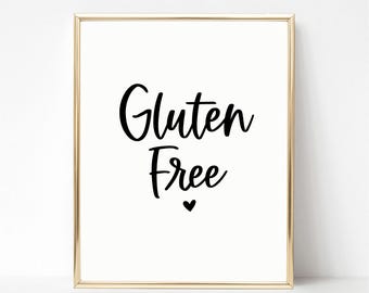 Può includere: Una stampa incorniciata con le parole "Gluten Free" in corsivo nero, con un piccolo cuore sotto. La stampa ha uno sfondo bianco ed è racchiusa in una cornice dorata.