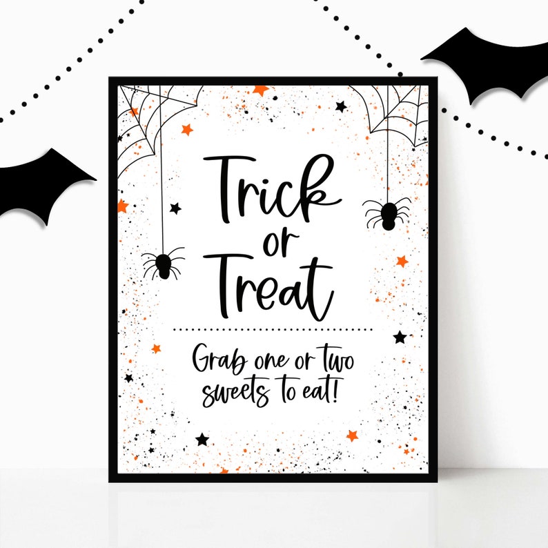 May include: A black and white printable sign with orange stars and spiderwebs. The sign says "Trick or Treat" and "Grab one or two sweets to eat!"