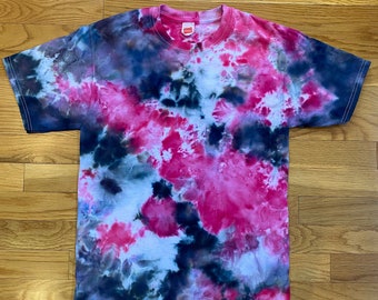 May include: A tie-dye t-shirt with a swirling pattern of pink, blue, and black.