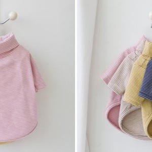 May include: Three striped turtleneck shirts for pets, one pink, one yellow, and one blue.