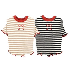 May include: Two pet shirts, one tan and one black, both with horizontal stripes. Each shirt has a red collar, a red bow detail, and red ruffled edges on the sleeves and hem. The shirts are designed for small dogs or cats.
