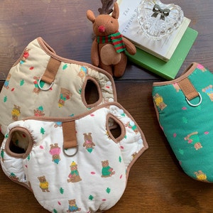 Peut inclure: Trois harnais pour chien avec un imprimé d'ours brun. Un harnais est vert, un autre est brun et le dernier est blanc avec des finitions brunes. Les harnais ont des sangles réglables et un anneau métallique pour attacher une laisse.