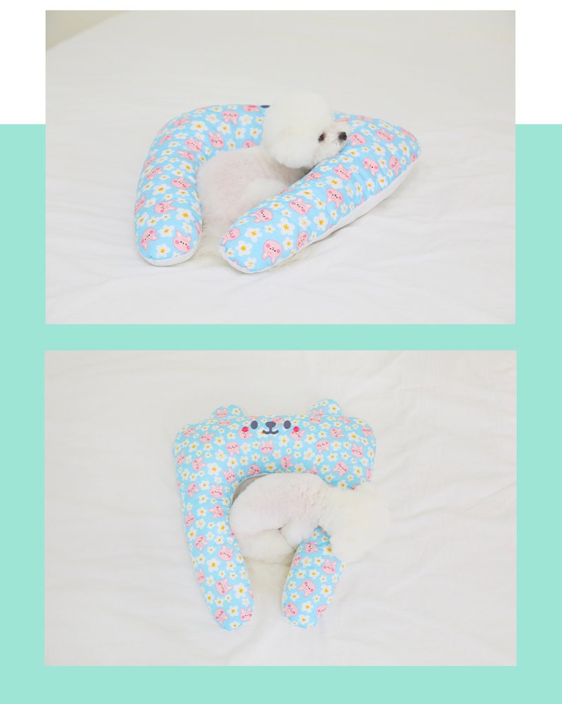 May include: A light blue and white patterned dog bed shaped like a horseshoe with a small white dog sleeping inside.
