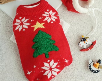 May include: Red knitted dog sweater with a white snowflake pattern and a green Christmas tree applique. The sweater has a yellow star on top of the tree.