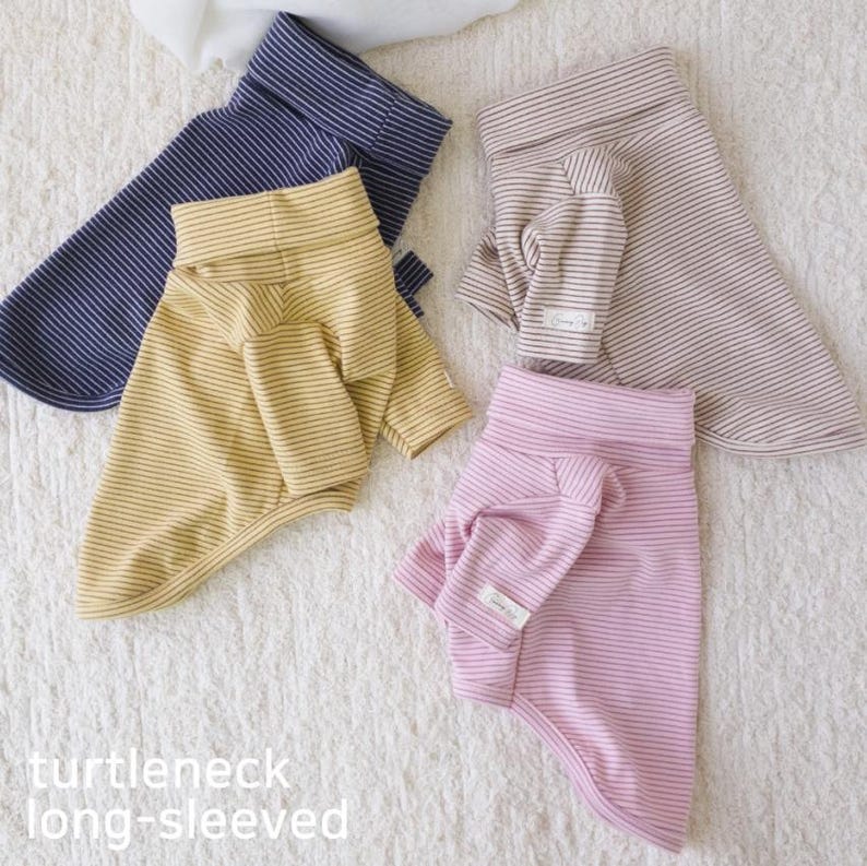 May include: Three striped long-sleeved shirts for pets. The shirts are in navy blue, yellow, and pink. The shirts have a turtleneck style.