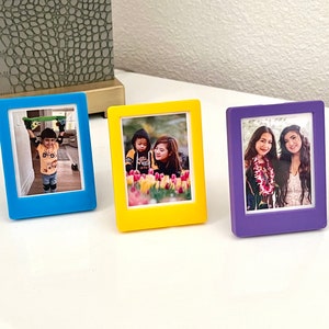 Personalizable Instax Mini Picture Frame with protective acrylic, built-in stand to put on tabletop, and embedded magnets to put on fridge