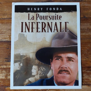Peut inclure: Affiche de film mettant en scène Henry Fonda portant un chapeau de cowboy. L'affiche est pour le film "La Poursuite Infernal" et présente un design de style vintage.