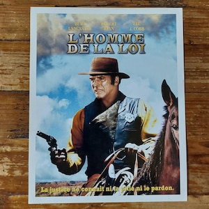 Peut inclure: Affiche de film vintage pour le film "L'Homme de la Loi" avec Burt Lancaster, Robert Ryan et Lee J. Cobb. L'affiche présente une image en noir et blanc d'un homme en chapeau de cowboy à cheval. Le texte sur l'affiche est en français.