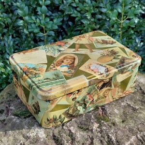 Peut inclure: Une boîte en métal rectangulaire vintage avec un collage d'images colorées sur le couvercle. Les images comprennent des fleurs, des enfants et des paysages. La boîte en métal est en bon état avec quelques signes d'usure.