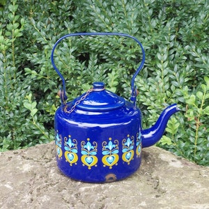 Könnte beinhalten: Eine blaue Emaille-Teekanne mit einem goldenen und blauen Blumendesign. Die Teekanne hat einen Deckel und einen Henkel.
