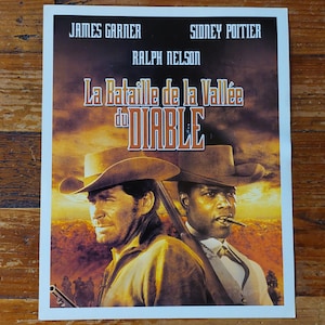 Peut inclure: Affiche de film pour le film "La Bataille de la Vallée du DIABLE" avec James Garner, Sidney Poitier et Ralph Nelson. L'affiche présente un gros plan des deux acteurs principaux, Garner et Poitier, portant des chapeaux de cow-boy, regardant le spectateur.