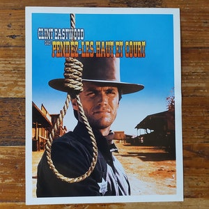 Könnte beinhalten: Ein Vintage-Filmplakat mit Clint Eastwood in einem Cowboyhut und einer Schlinge um den Hals. Das Plakat ist blau und weiß mit dem Text "Clint Eastwood dans Pendez-Les Haut Et Court".