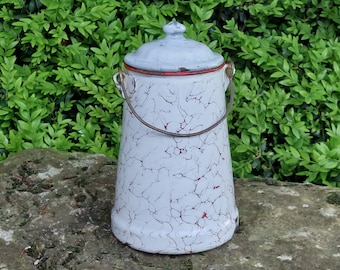 May include: A white enamelware pitcher with a red rim and a white lid. The pitcher has a crackled glaze and a wire handle.