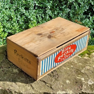 May include: A wooden box with a blue and white striped lid. The box is labeled "Reckitt's Blue" and "Bleu Reckitt En Carres".