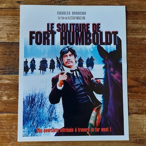 Peut inclure: Affiche de film vintage pour le film "Le Solitaire de Fort Humboldt" avec Charles Bronson. L'affiche présente une image dramatique de Bronson à cheval et tenant une arme à feu, avec un paysage enneigé en arrière-plan. Le texte sur l'affiche est en français.