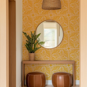 May include: A well-lit entryway with a yellow patterned wallpaper and a round mirror. A wooden console table holds a potted plant. Two brown leather ottomans sit on the floor. A woven pendant light hangs from the ceiling.