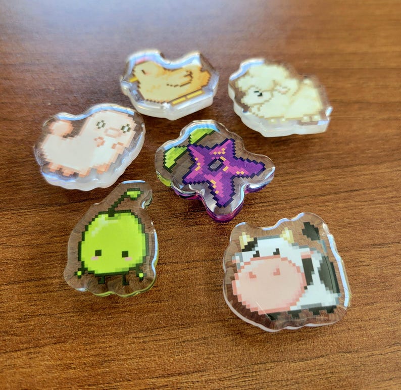 Six shoe charms sitting on a desk. The six shoe charms are: Silk worm, junimo, chicken, sheep, stardop, and cow