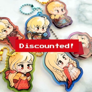 May include: A collection of anime-style character keychains with various designs and colors. Each keychain features a cartoon character with blonde hair and a unique outfit. A red banner with the text "Discounted!" is across the image.