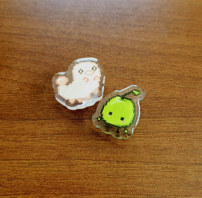 Two shoe charms sitting on a desk. The two charms are silk worm and junimo