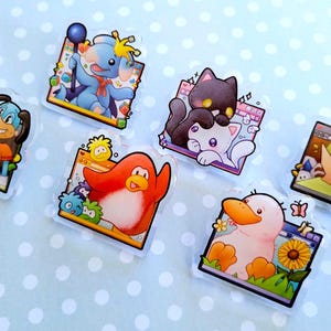 May include: A collection of colorful, cartoon-style acrylic charms featuring various animals and characters. Each charm is set against a digital interface frame, with vibrant details and playful designs. The charms include a dog, elephant, cat, penguin, duck, and a green-hatted character.