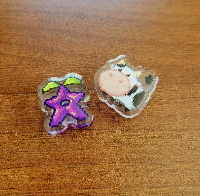 Two shoe charms sitting on a desk. The two charms are stardrop and cow