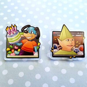May include: Two cartoon-style stickers. One features a blue dog holding a birthday cake with candles, wearing an orange shirt and purple pants. The other shows a green-clad elf-like character in front of a computer screen. Both stickers have a clear border.