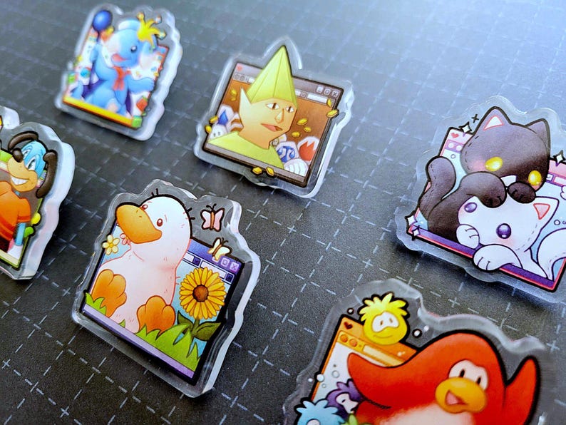 May include: A collection of clear acrylic pins featuring cartoon characters. Designs include a blue elephant, a duck with a sunflower, a penguin, a dog, a cat, and a character with a green hat. Each pin has a unique shape and colorful details.