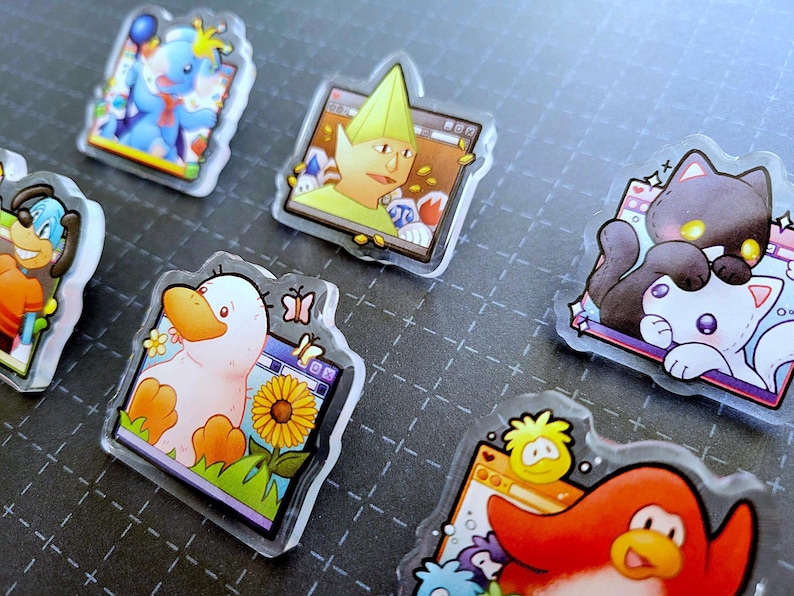 May include: A collection of clear acrylic pins featuring cartoon characters. Designs include a blue elephant, a duck with a sunflower, a penguin, a dog, a cat, and a character with a green hat. Each pin has a unique design and color scheme.