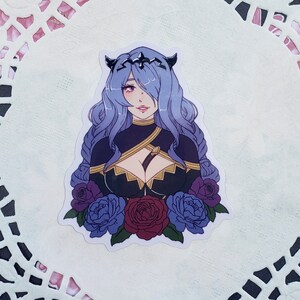 May include: A sticker featuring a woman with purple hair, wearing a crown and a black and gold outfit. She is surrounded by blue and red roses.