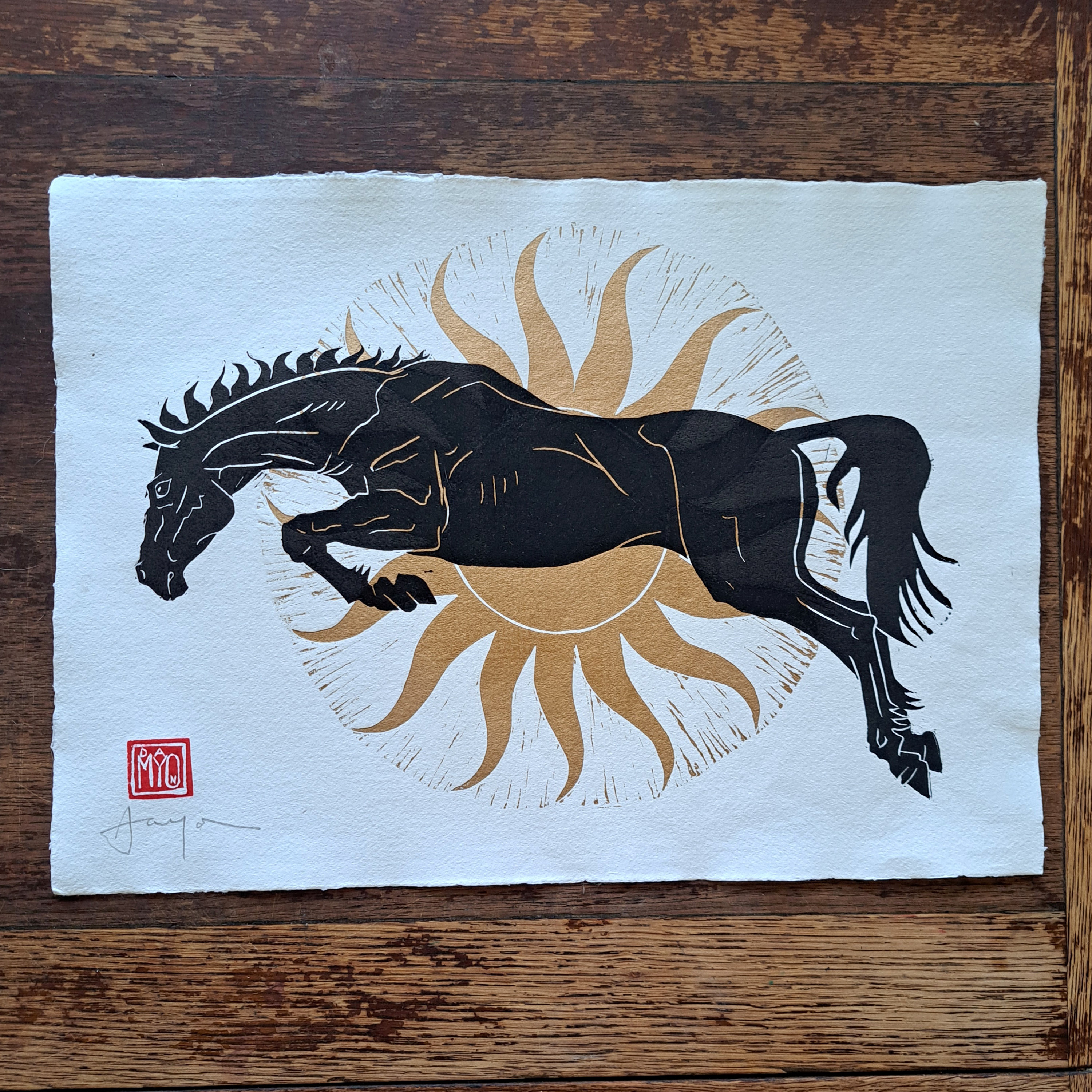 太陽の馬。金色の太陽の前でジャンプする黒馬のオリジナルリノカット