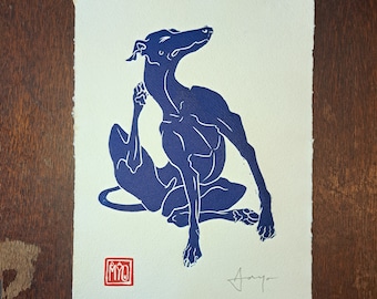 May include: A blue silhouette of a dog sitting on its haunches, with its head tilted back and its tongue out. The dog is in a relaxed pose, with its legs stretched out in front of it. The image is printed on a white background.