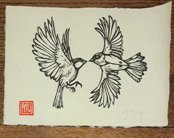 Op de afbeelding: Zwart-witte houtsnede van twee vogels die elkaar aankijken met gespreide vleugels. De vogels zijn in een eenvoudige, minimalistische stijl. De print is onderaan links gesigneerd met "Myo" en onderaan rechts met "Jayne".