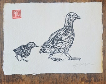 May include: Black and white linocut print of two birds. The larger bird is standing with its wings spread. The smaller bird is standing with its head turned to the side. The print is signed "Tanya".