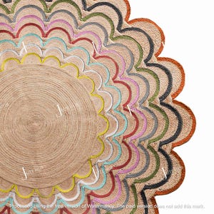 Può includere: Tappeto rotondo in juta con bordo smerlato. Il tappeto presenta un centro beige naturale e un bordo decorativo con cuciture colorate nei toni del giallo, turchese, rosa, rosso e verde. Un elemento decorativo per la casa.