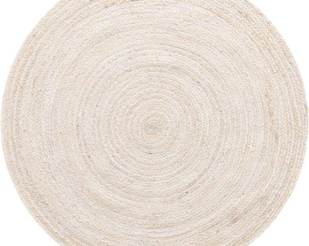 May include: A round, natural-toned jute rug. The rug is woven in a spiral pattern, creating concentric circles from the center outward. The neutral color and texture suggest a casual, earthy aesthetic, suitable for various interior styles.
