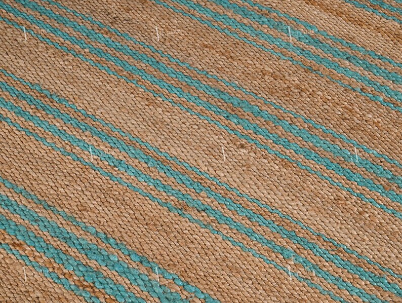 Op de afbeelding: Close-up van een geweven tapijt met een natuurlijke bruine achtergrond en diagonale strepen in turquoise blauw. Het tapijt heeft een textuur en de strepen zijn gelijkmatig verdeeld.