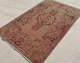 May include: A vintage rug with a faded red and green floral pattern. The rug has a worn, distressed look and is perfect for adding a touch of bohemian style to any room.