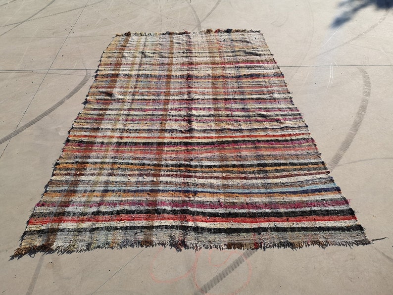 May include: A multi-colored striped rug with a frayed edge. The rug is made of woven fabric and has a rustic, vintage look.