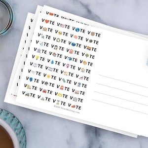 May include: A stack of white postcards featuring the repeated black text VOTE with various colorful emojis replacing the letter O. The right side has lines for an address and a blue postage stamp with a red fish illustration. The text VoterMailbag.com is at the bottom.