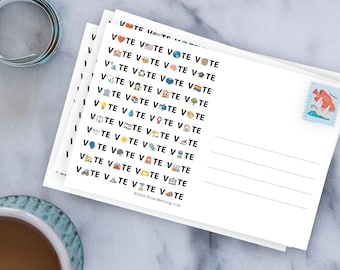 May include: A stack of white postcards featuring the repeated black text VOTE with various colorful emojis replacing the letter O. The right side has lines for an address and a blue postage stamp with a red fish illustration. The text VoterMailbag.com is at the bottom.